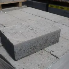 Stos szarych bloczków betonowych fundamentowych, gotowych do budowy solidnych podstaw.