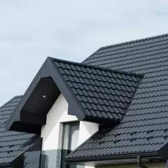 Nowoczesny, ciemnoszary dach dwuspadowy 200m2. Elegancka blachodachówka z widocznym kominem i okapem.