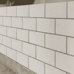 Ściana z jasnych, gładkich cegieł, prezentująca różne rodzaje cegieł w nowoczesnej architekturze.