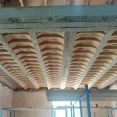 Widok od dołu na strop gęstożebrowy z betonowymi belkami i pustakami ceramicznymi.