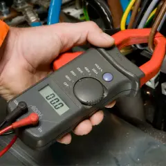 Elektryk mierzy prąd, sprawdzając potencjalny spadek napięcia w instalacji.