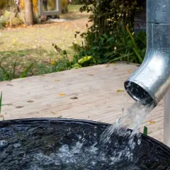 Woda z rynien spływa do czarnego zbiornika, zbierając deszczówkę.