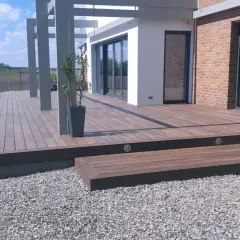 Nowoczesny taras wentylowany, choć piękny, może mieć wady. Widoczna przestrzeń wokół domu z drewnianym tarasem i elementami architektonicznymi.