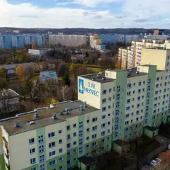 Osiedle bloków z wielkiej płyty S.M. Młyniec w jesiennej scenerii. Długie, wielopiętrowe budynki mieszkalne dominują w krajobrazie.