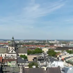 Widok na krakowskie dachy i kościół z kopułą. W tle nowoczesne budynki, które mogą wpływać na ceny mieszkań Kraków.