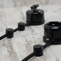 Elegancka instalacja elektryczna natynkowa w stylu retro. Czarne, ceramiczne gniazdko i wyłącznik na elastycznym przewodzie.