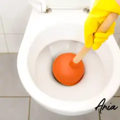 Ręka w żółtej rękawiczce używa przepychacza do toalety. Prosty sposób, jak odetkać kibel, gdy się zapcha.