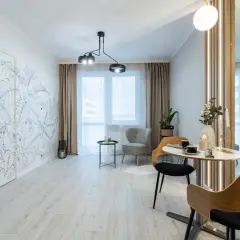 Nowoczesny salon z motywem roślinnym na ścianie. Wygodne fotele i stolik kawowy tworzą przytulną przestrzeń, idealną do relaksu. To wnętrze z rynku wtórnego zachwyca stylem.