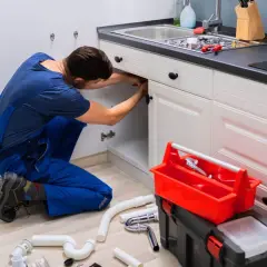 Hydraulik naprawia instalację pod zlewem. Sprawdź nasze usługi hydrauliczne cennik.
