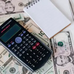 Kalkulator, notatnik i długopis leżą na banknotach. Obliczanie, ile kosztuje m3 gazu, wymaga dokładności.