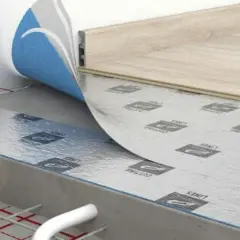Warstwa izolacyjna pod panele laminowane, z folią aluminiową i niebieskim wykończeniem, na podłożu z ogrzewaniem podłogowym.