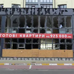 Uszkodzony budynek z banerem "GOTOWI KWARTRYRY від 923 000 ГРН". Zastanawiasz się, ile kosztuje mieszkanie na Ukrainie?