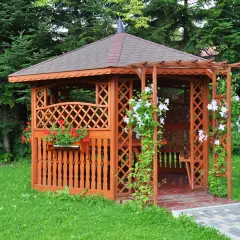Urocza altana na działce ROD, otoczona zielenią, z kwitnącymi pnączami i pelargoniami. Idealne miejsce na relaks.