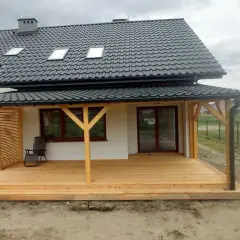 Nowy, drewniany taras w trakcie budowy, z widocznymi słupami i deskami. Idealne miejsce na letnie wieczory.