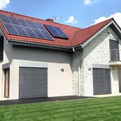 Nowoczesny dom z panelami solarnymi na dachu. Elegancka elewacja i zadbany ogród.