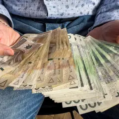 Ręce trzymające plik banknotów. To może być darowizna 200 tysięcy od rodziców, wsparcie finansowe.