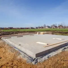 Budowa fundamentów cena: betonowa płyta na placu budowy, drewno przygotowane do dalszych prac.