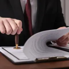 Prawnik pieczętuje dokumenty, które mogą dotyczyć ustalenia, ile wynosi podatek od spadku mieszkania.