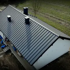 Nowy dach z blachy Budmat. Cennik dostępny online. Dom w trakcie budowy, otoczony zielenią.
