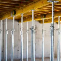 Konstrukcja pod strop monolityczny: szeregi metalowych podpór i drewniane belki tworzą rusztowanie.