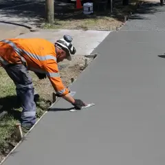 Robotnik wygładza świeży beton. Zastanawiasz się, ile kosztuje kubik betonu na podjazd?