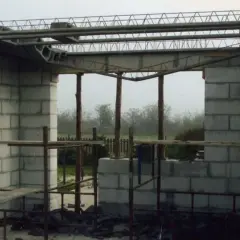 Zbrojenie stropu zasady w budowie. Betonowe bloki tworzą ściany, a nad nimi widać stalowe belki i kratownice.