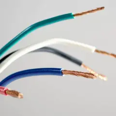 Pięć przewodów elektrycznych w różnych kolorach: zielonym, białym, czarnym, niebieskim i różowym, odsłaniających miedziane żyły. Różnorodne kolory faz.