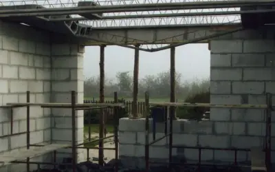 Zbrojenie stropu zasady w budowie. Betonowe bloki tworzą ściany, a nad nimi widać stalowe belki i kratownice.
