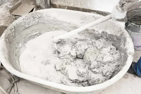 Mieszanie wapna gaszonego z wodą w dużej misie, tworząc gładką masę budowlaną.