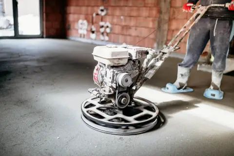Pracownik wygładza posadzkę mechanicznie. Sprawdź, jaka jest wylewka styrobeton cena za m2.