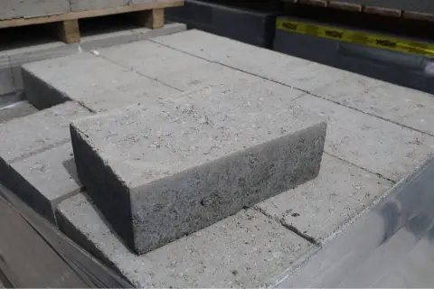 Stos szarych bloczków betonowych fundamentowych, gotowych do budowy solidnych podstaw.
