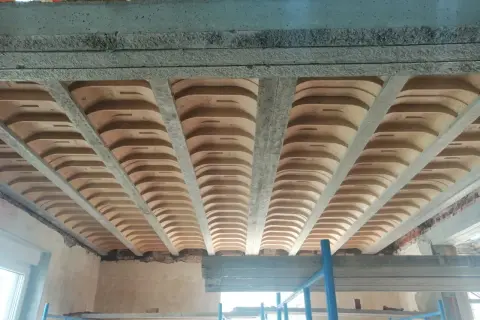 Widok od dołu na strop gęstożebrowy z betonowymi belkami i pustakami ceramicznymi.