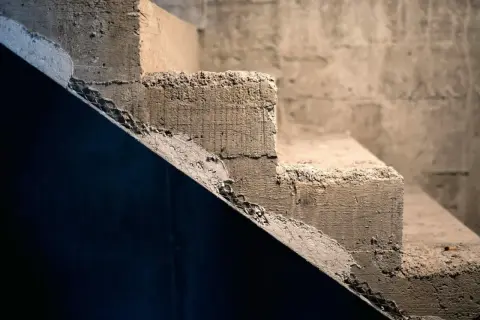 Surowe schody betonowe, idealne do rozważenia, jak tanio wykończyć schody betonowe. Widoczne nierówności i siatka zbrojeniowa.
