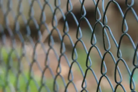 Siatka ogrodzeniowa w trakcie montażu, tworząca charakterystyczny wzór rombów.