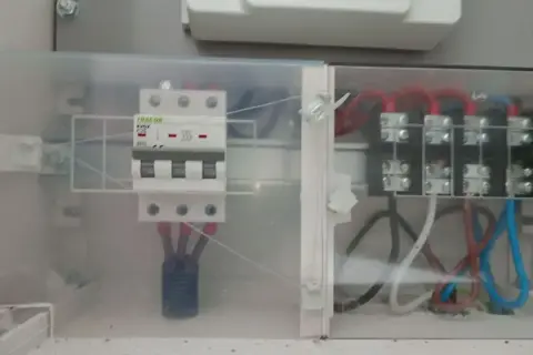 W skrzynce elektrycznej widoczny jest zabezpieczenie przedlicznikowe TRACON, połączone z innymi przewodami.