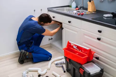 Hydraulik naprawia instalację pod zlewem. Sprawdź nasze usługi hydrauliczne cennik.