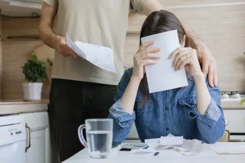 Kobieta zakrywa twarz papierem, mężczyzna kładzie rękę na jej ramieniu.