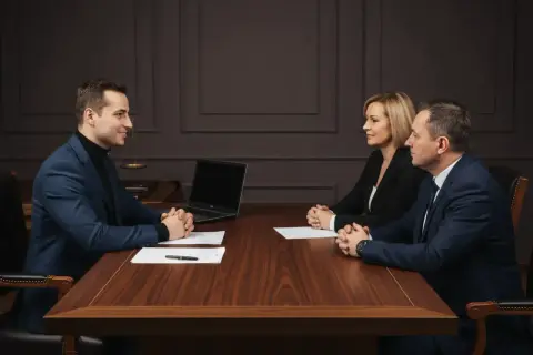 Notariusz omawia akt notarialny mieszkania z klientami przy drewnianym stole.