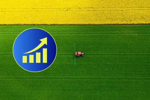 Wykres wzrostu na tle pola rzepaku i zielonej łąki, gdzie pracuje traktor. Zastanawiasz się, ile kosztuje hektar ziemi?