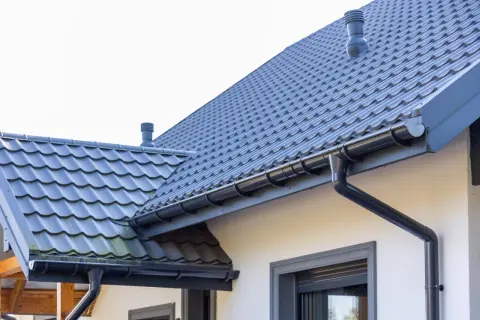 Szary dach z dachówki ceramicznej, rynny i komin. Sprawdź, jaka jest dachówka ceramiczna cena za m2 dla Twojego domu.