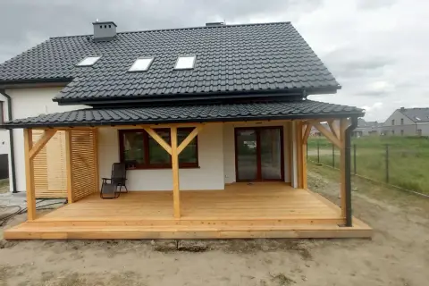 Nowy, drewniany taras w trakcie budowy, z widocznymi słupami i deskami. Idealne miejsce na letnie wieczory.