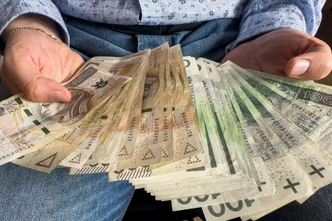 Ręce trzymające plik banknotów. To może być darowizna 200 tysięcy od rodziców, wsparcie finansowe.