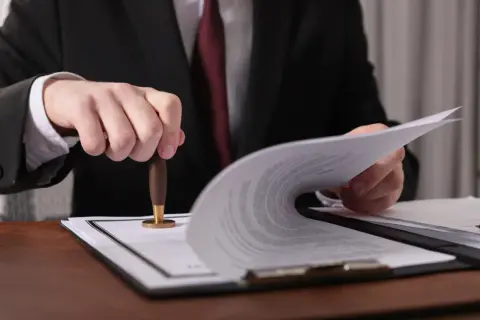 Prawnik pieczętuje dokumenty, które mogą dotyczyć ustalenia, ile wynosi podatek od spadku mieszkania.