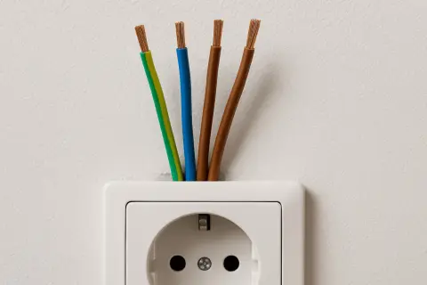 Cztery przewody wychodzące z gniazdka elektrycznego. Zastanawiasz się, jaki kabel do indukcji będzie najlepszy?