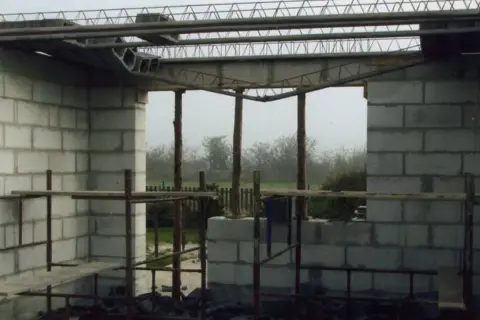 Zbrojenie stropu zasady w budowie. Betonowe bloki tworzą ściany, a nad nimi widać stalowe belki i kratownice.