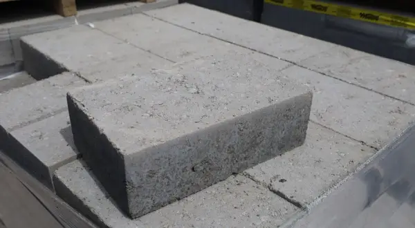 Stos szarych bloczków betonowych fundamentowych, gotowych do budowy solidnych podstaw.