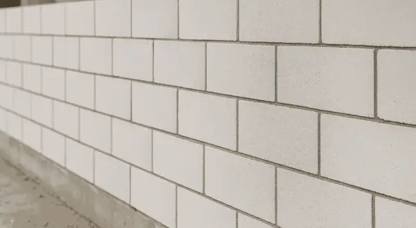 Ściana z jasnych, gładkich cegieł, prezentująca różne rodzaje cegieł w nowoczesnej architekturze.