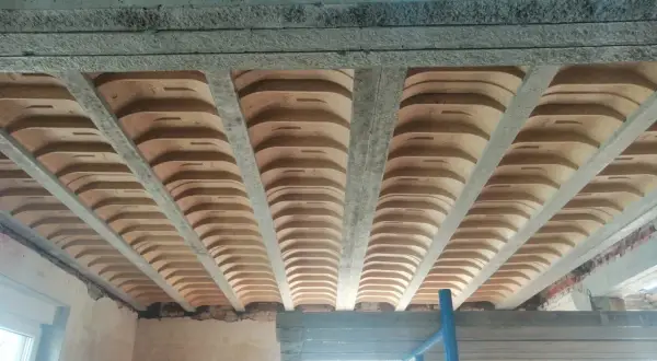 Widok od dołu na strop gęstożebrowy z betonowymi belkami i pustakami ceramicznymi.