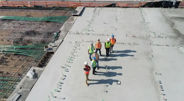 Grupa budowlańców na placu budowy. Widać zbrojenie i świeży beton. Sprawdzają beton b25 cena za m3.