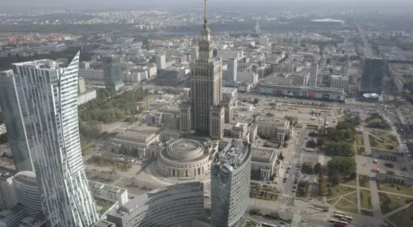 Widok z lotu ptaka na centrum Warszawy, gdzie widać Pałac Kultury i Nauki, jeden z najwyższych budynków w Polsce, otoczony nowoczesnymi wieżowcami.
